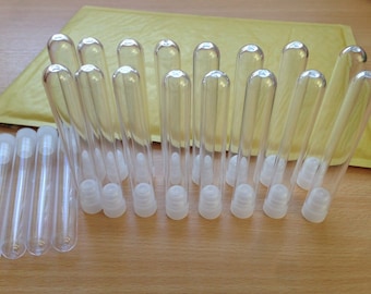 May include: A set of 20 clear plastic tubes with white caps. The tubes are approximately 10 cm long and 1 cm in diameter. The tubes are arranged in two rows, with the caps facing up.