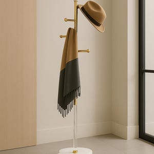 May include: A modern coat rack with a clear acrylic pole and a white marble base. It features brass hooks, a tan fedora hat, and a two-tone scarf in tan and dark green. The rack is in a neutral-toned room.