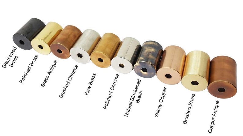 May include: A selection of cylindrical metal objects in finishes such as blackened brass, polished brass, and copper antique. Each cylinder has a central hole. Text labels identify each finish.
