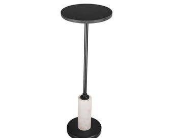 May include: A contemporary side table with a circular black top and base, joined by a thin black metal pole. The central column has a white marble cylinder. The table is designed for indoor use.