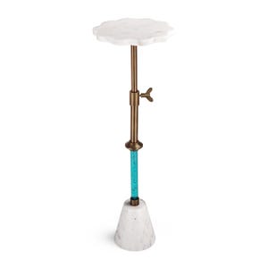 May include: A tall, decorative side table with a white marble cloud-shaped top. The adjustable brass-colored stem features a turquoise glass section and a marble cone-shaped base. The table is designed for display or as a functional accent piece.