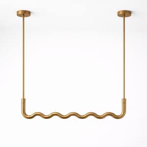 May include: A gold-coloured, wavy-shaped light fixture suspended from the ceiling. The fixture has a series of curves and is attached to the ceiling with two straight rods. The design is minimalist and modern.