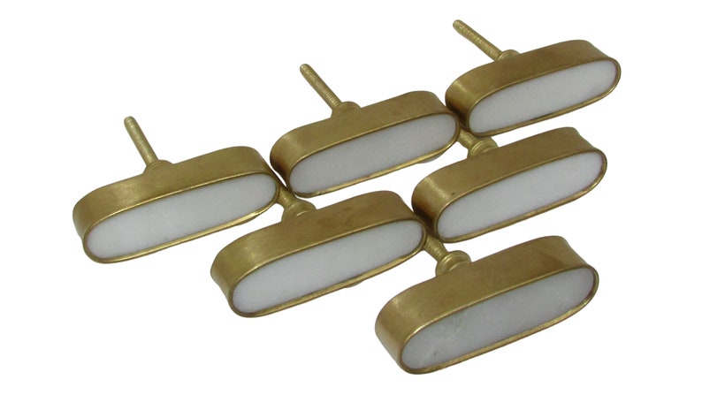 May include: Six brass cabinet knobs with a white, oval-shaped center. The knobs have a simple, elegant design, perfect for adding a touch of sophistication to furniture or cabinetry. Each knob has a stem for easy installation.
