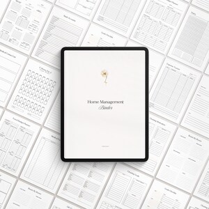 May include: A digital tablet displaying a white background with the text "Home Management Binder" in black font. A small watercolor illustration of a white flower is in the top center of the screen. The tablet is surrounded by various printable pages for a home management binder.