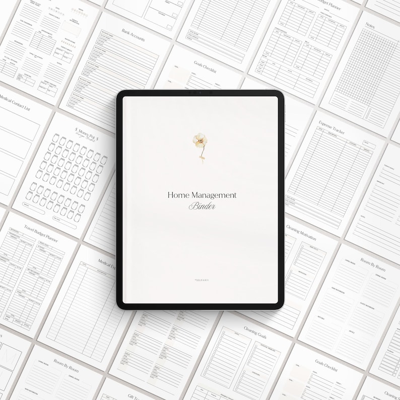 May include: A digital tablet displaying a white background with the text "Home Management Binder" in black font. A small watercolor illustration of a white flower is in the top center of the screen. The tablet is surrounded by various printable pages for a home management binder.