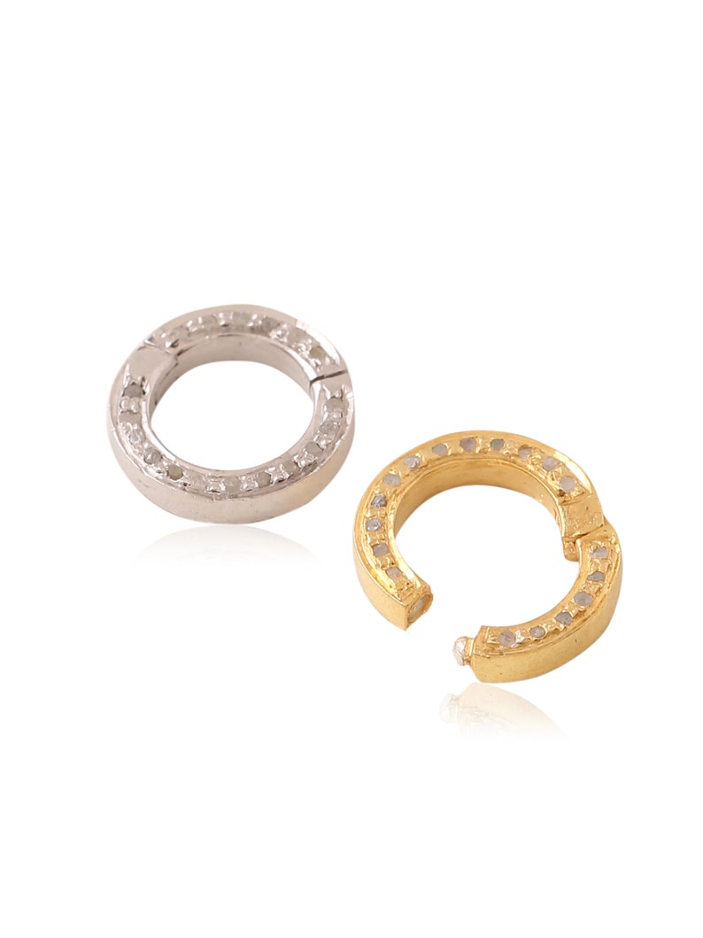 K&ouml;nnte beinhalten: Zwei Ringe aus Silber und Gold mit einer Reihe kleiner Diamanten am Rand. Die Ringe sind offen und haben einen Scharnierverschluss.