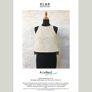 May include: A white sleeveless top with a scoop neck, made from linen fabric, is displayed on a mannequin against a white brick wall. The text "A Leiberl aus Leinen" is written in blue on a white background below the top. The text "Stoffempfehlung: Leinen" is written in black on a white background below the blue text. The text "Benötigte Stoffmenge: 0,6m (bei 140cm Stoffbreite)" is written in black on a white background below the black text.