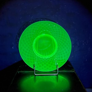 May include: A green glass plate with a textured surface. The plate is on a metal stand.