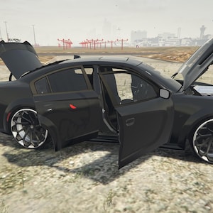 Puede incluir: Un sedán negro con el capó, el maletero y las puertas abiertos, revelando el interior y el motor. El coche tiene llantas personalizadas en negro y plata. El vehículo está estacionado sobre una superficie de tierra.