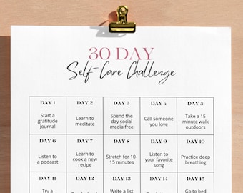 May include: A printable 30-day self-care challenge chart with daily activities listed in a grid format. The chart is on a white background with pink text and a gold paper clip in the top left corner.