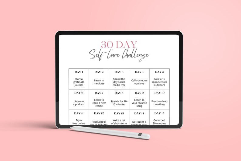 May include: A digital tablet displaying a 30-day self-care challenge with daily activities, such as starting a gratitude journal, learning to meditate, and taking a walk outdoors. The tablet is on a pink surface with a stylus next to it.
