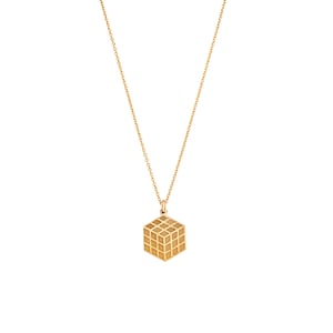 May include: A gold necklace with a geometric cube pendant. The cube has a grid pattern.