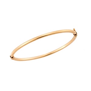 Könnte beinhalten: Ein schlichtes goldenes Armreif-Armband mit einem Scharnierverschluss.