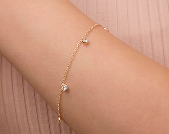 May include: A delicate gold chain bracelet with small round clear stones dangling from it.