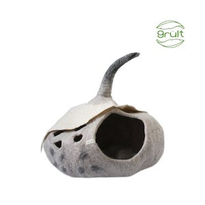 Może przedstawiać: Szare filcowe legowisko dla kota w kształcie dyni z czarnym filcowym ogonem. Legowisko ma biały filcowy dach z wyciętymi otworami i małą etykietę z napisem "gr&uuml;lt".