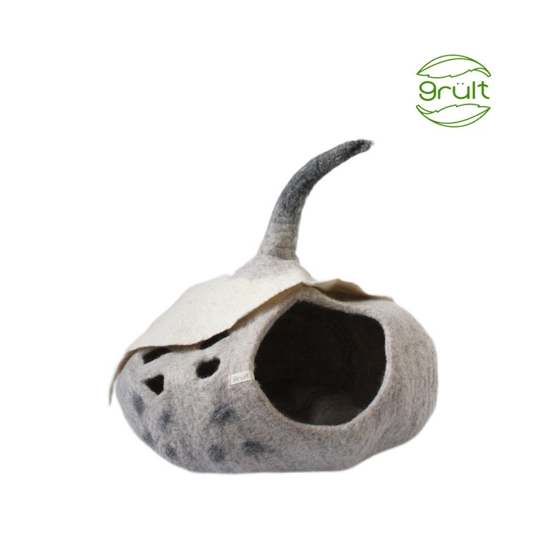 Może przedstawiać: Szare filcowe legowisko dla kota w kształcie dyni z czarnym filcowym ogonem. Legowisko ma biały filcowy dach z wyciętymi otworami i małą etykietę z napisem "gr&uuml;lt".