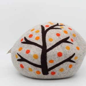 Może przedstawiać: Szara poduszka z filcu w kształcie skały z brązowym wzorem drzewa i pomarańczowymi i ż&oacute;łtymi kropkami z filcu.