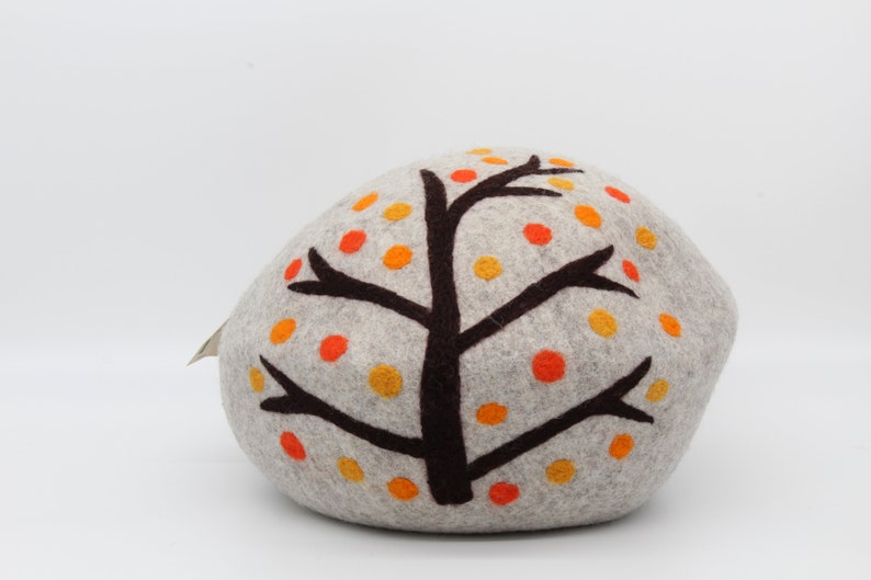Może przedstawiać: Szara poduszka z filcu w kształcie skały z brązowym wzorem drzewa i pomarańczowymi i ż&oacute;łtymi kropkami z filcu.