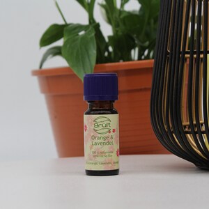 May include: A small, brown glass bottle with a purple cap. The bottle is labeled "gr&uuml;t Orange & Lavendel 100% nat&uuml;rliche &auml;therische &Ouml;le Orange, Lavendel, Orange"