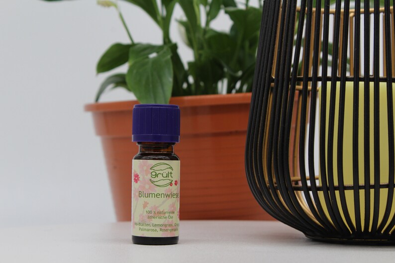 May include: A small, dark brown glass bottle with a purple lid. The bottle is labeled "gr&uuml;t" and "Blumenwiese". The label also says "100% nat&uuml;rliche &auml;therische &Ouml;le".