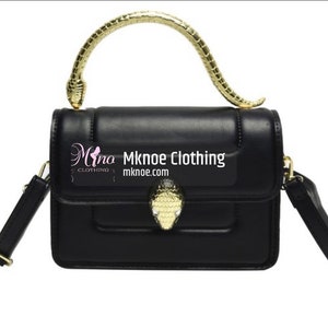 May include: A black rectangular handbag featuring a gold-toned snake-shaped handle and a matching snake head clasp on the front flap. The bag includes an adjustable black shoulder strap and displays the text Mknoe Clothing mknoe.com on the front.