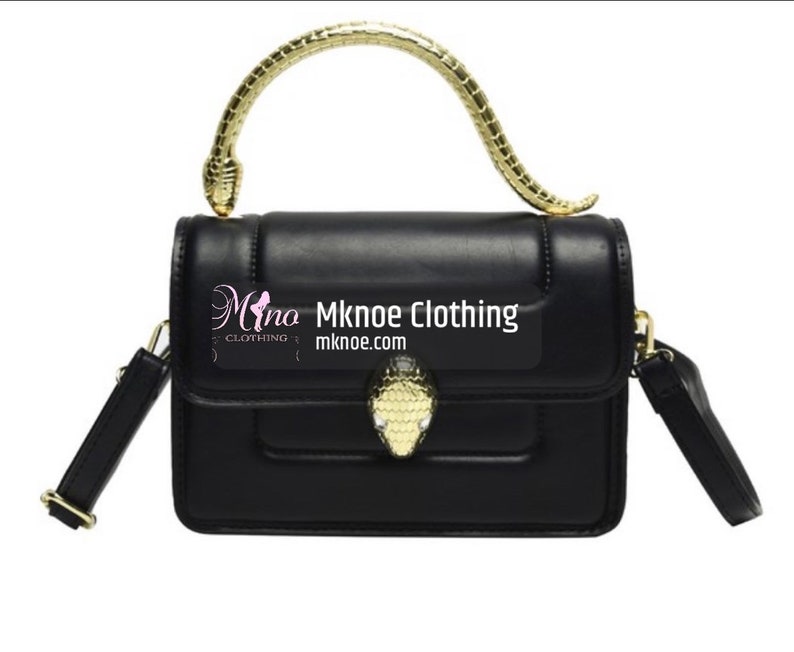 May include: A black rectangular handbag featuring a gold-toned snake-shaped handle and a matching snake head clasp on the front flap. The bag includes an adjustable black shoulder strap and displays the text Mknoe Clothing mknoe.com on the front.