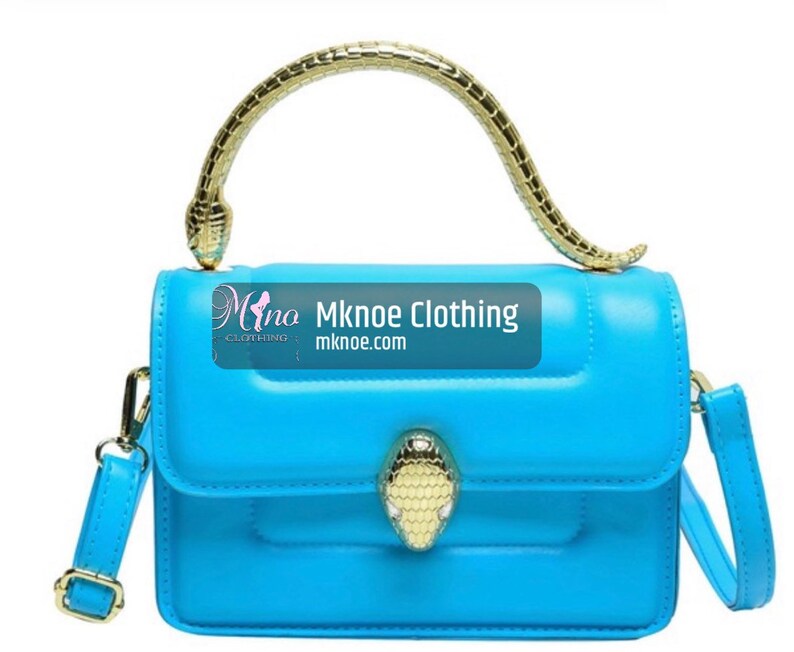 May include: A bright blue handbag featuring a gold-toned snake-shaped handle and a matching snake head clasp on the front flap. The bag includes a detachable shoulder strap and displays the text Mknoe Clothing mknoe.com on the front surface.