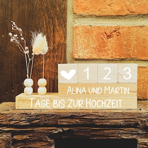Könnte beinhalten: Holz-Countdown-Block mit einem Herzen, den Zahlen 1, 2, 3 und dem Text "Alina und Martin Tage bis zur Hochzeit".
