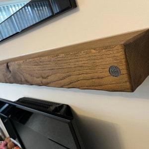 May include: A rustic wooden shelf with a natural wood finish. The shelf has a rough-hewn edge and a metal logo that reads "Funky Timber".