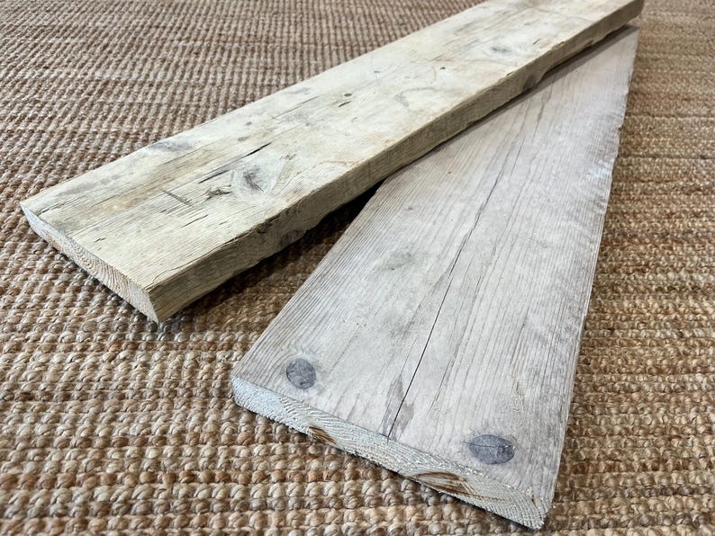 May include: Two rectangular wooden boards with a weathered, light gray finish. The boards feature visible wood grain, natural knots, and rough, textured surfaces. The wood displays signs of age with subtle cracks and variations in color tone.