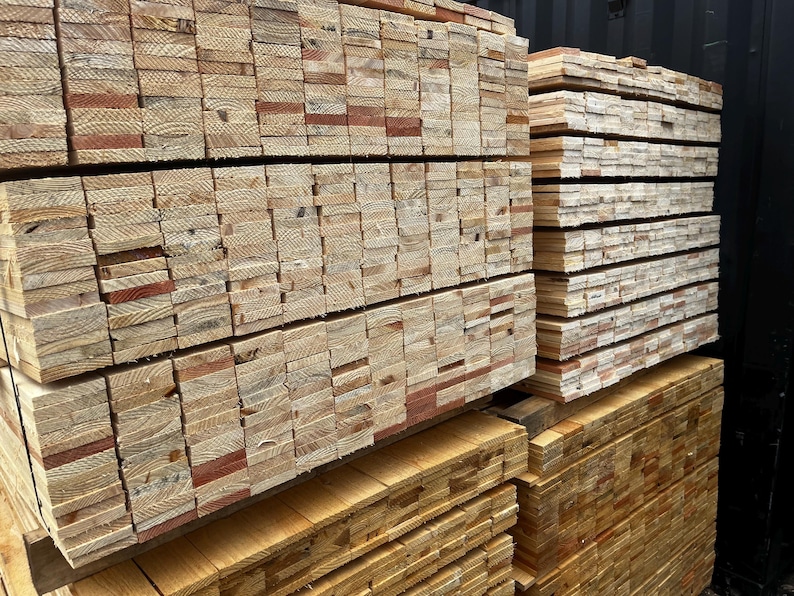 May include: Stacks of freshly cut lumber, showcasing the natural grain and color variations of the wood. The lumber is neatly arranged in layers, ready for construction or woodworking projects. The wood appears to be pine or a similar softwood.
