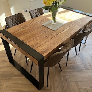 May include: A wooden dining table with a black metal frame, surrounded by six brown upholstered chairs. The table has a natural wood grain finish. A vase of yellow flowers sits on the table. The table is approximately 72 inches long.