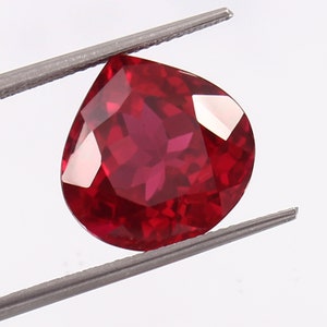 Può includere: Una pietra preziosa di forma a pera di colore rosso intenso con una taglio a forma di stella.