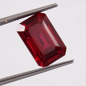 Könnte beinhalten: Ein tief roter Smaragdschliff-Edelstein mit hohem Glanz.