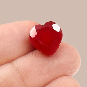 May include: A heart-shaped red gemstone with a faceted cut.