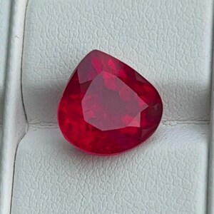 Könnte beinhalten: Ein tief roter birnenförmiger Edelstein mit Facetten.