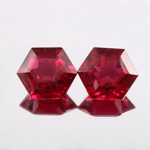Könnte beinhalten: Zwei rote sechseckige Edelsteine mit einem sternförmigen Muster im Inneren.
