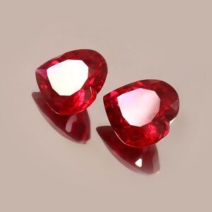 Può includere: Due pietre preziose rosse a forma di cuore con taglio a faccette.