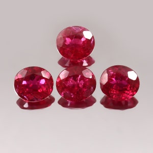 Könnte beinhalten: Vier runde, rote Edelsteine mit facettiertem Schliff. Die Edelsteine sind in Pyramidenform angeordnet.