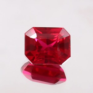 May include: A deep red gemstone with a square shape and a faceted cut.