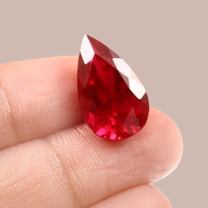 Könnte beinhalten: Ein birnenförmiger, tief roter Rubin-Edelstein.