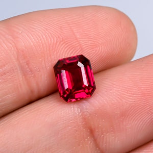 Könnte beinhalten: Ein tiefroter Edelstein mit einem rechteckigen Smaragdschliff.