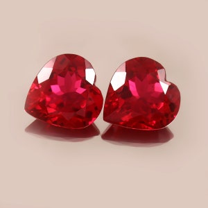 May include: Two heart-shaped red gemstones with a faceted cut.