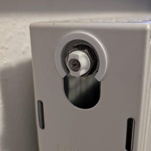 Könnte beinhalten: Nahaufnahme eines weißen Heizkörperventils mit einem weißen Kunststoffknopf. Das Ventil ist mit "Heimeier" beschriftet.