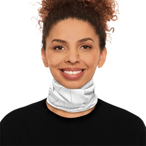 May include: A white neck gaiter with a black geometric pattern. The neck gaiter is worn by a person with curly brown hair.