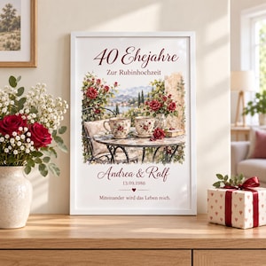以下が含まれることがあります： 「40 Ehejahre Zur Rubinhochzeit」、「Andrea & Ralf」、「13.09.1986」、「Miteinander wird das Leben reich」という文字が入った額入りプリント。花柄のティーカップ2つ、赤いバラ、風景が描かれたテーブルの画像。