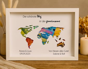 May include: A white picture frame with a world map cutout filled with colorful paper money. The text "Der schönste Weg ist der gemeinsame" is at the top of the frame. The names "Ariane & Louis" and the date "09.09.2025" are at the bottom left of the frame. The text "Von Herzen alles Gute Sabine & Rolf" is at the bottom right of the frame.