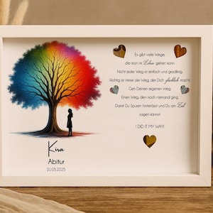 May include: A white framed picture with a rainbow tree and a quote about finding your own path. The quote reads, "Es gibt viele Wege, die man im Leben gehen kann. Nicht jeder Weg ist einfach und gradlinig. Richtig ist immer der Weg der dich gl&uuml;cklich macht. Geh deinen eigenen Weg. Einen Weg, den noch niemand ging. Damit du Spuren hinterl&auml;sst und du am Ziel sagen kannst: I DID IT MY WAY!" The picture also includes the text "Kira Abitur 31.05.2025".