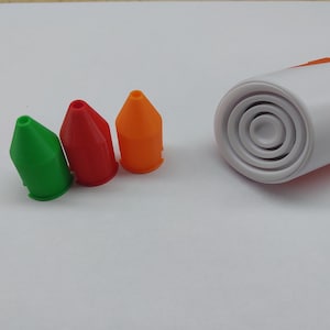 Könnte beinhalten: Drei unterschiedlich farbige Kunststoffspitzen für einen 3D-Druck-Stift. Die Spitzen sind grün, rot und orange. Die Spitzen sind von links nach rechts in einer Reihe angeordnet. Der 3D-Druck-Stift ist nicht im Bild zu sehen.