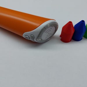 Könnte beinhalten: Ein orangefarbenes und weißes Zeichenwerkzeug mit drei farbigen Spitzen: rot, blau und grün.